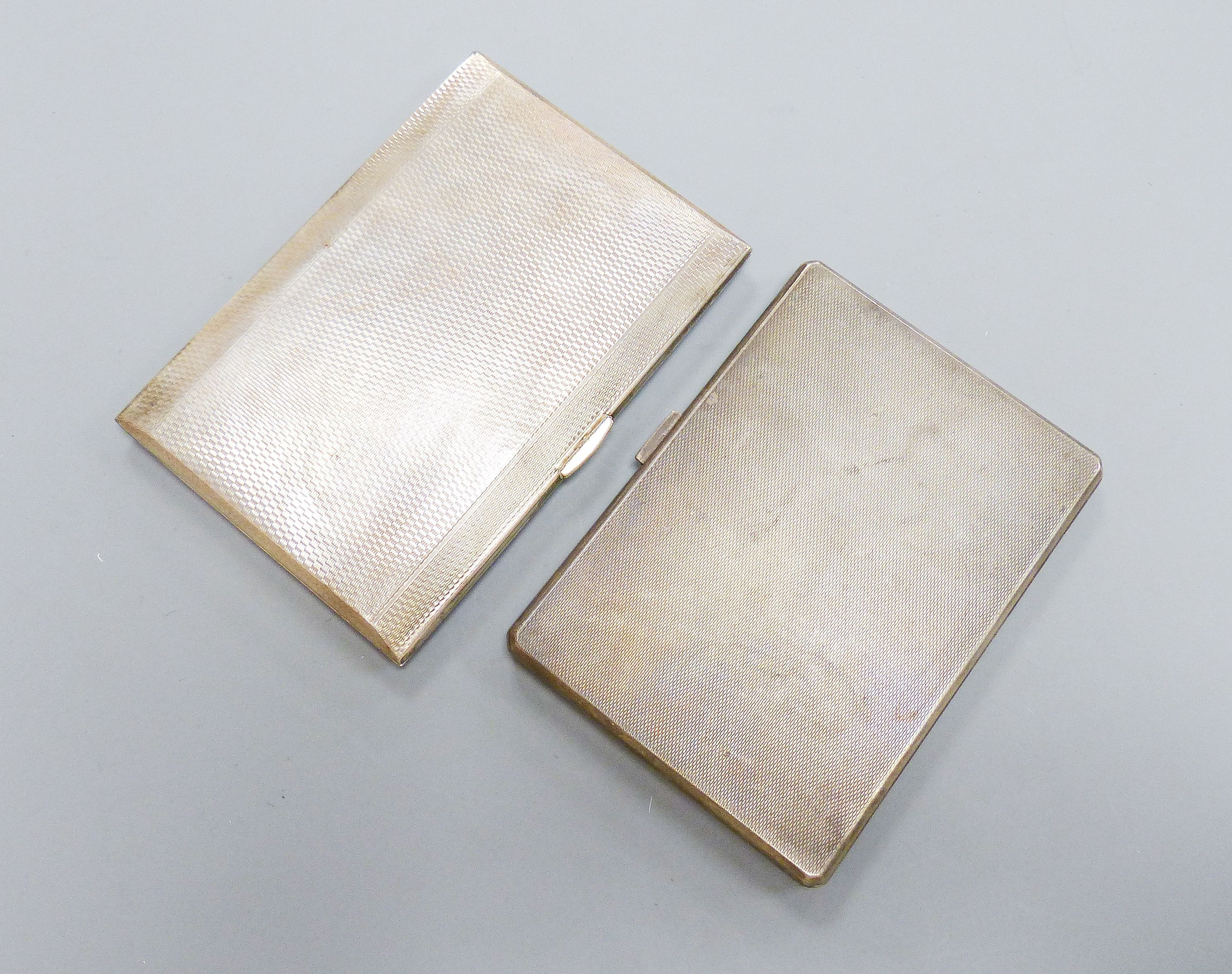 Two George V engine turned silver cigarette cases, largest 12.4cm, gross 12.5oz.